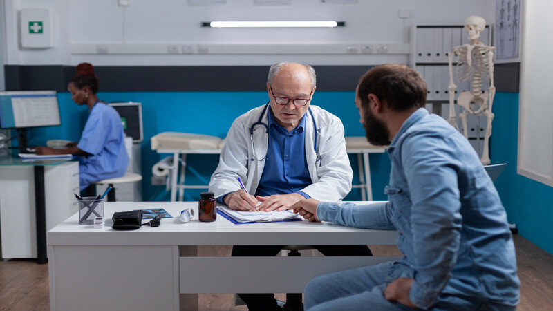 Man doctor signing checkup files to give treatment and medical advice to patient